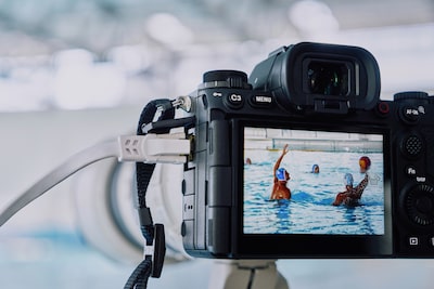 Imagen de uso de la cámara montada en un trípode y conectada a un cable LAN que hace capturas a un partido de waterpolo con una imagen en vivo que se muestra en el monitor LCD