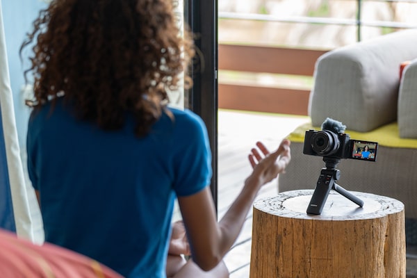 Imagen de una modelo filmándose con una cámara en un minitrípode sobre una mesa y una pantalla de ángulo variable extendida para verse.